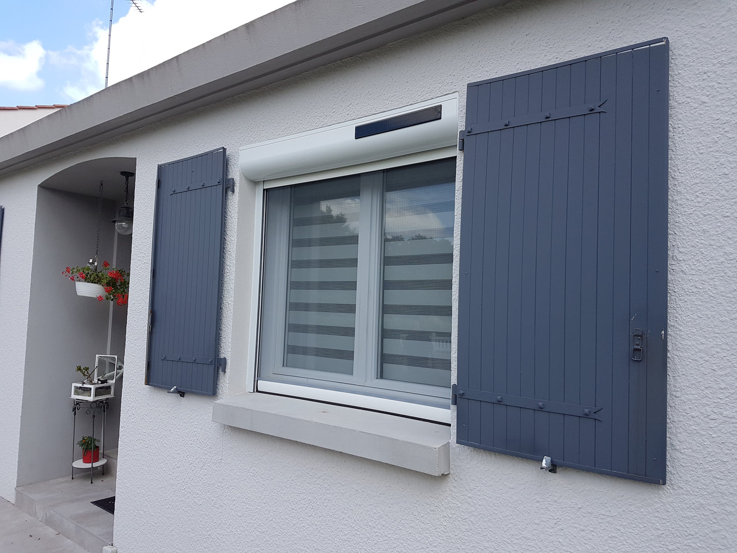 Volet roulant sur mesure en aluminium blanc avec moteur Somfy solaire et moustiquaire – fabriqué en France, installation sous linteau avec pan quart de rond pour fenêtre
