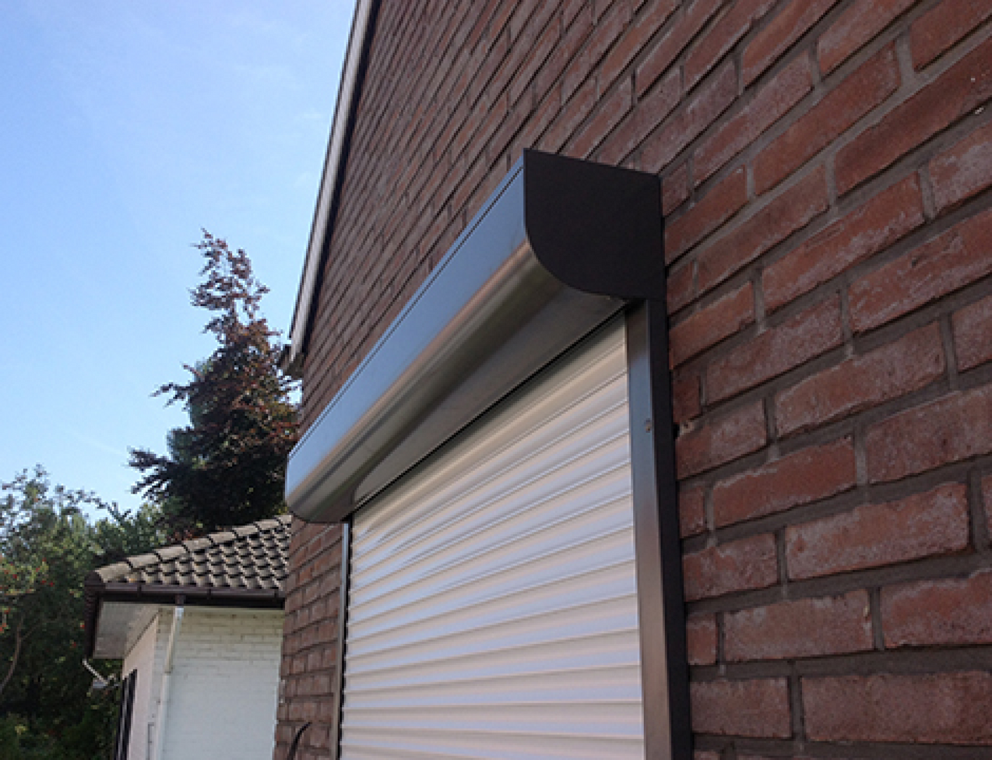 Volet roulant sur mesure en aluminium avec coffre noir, tablier blanc et moteur Somfy – fabriqué en France, installation en façade avec pan quart de rond pour porte terrasse